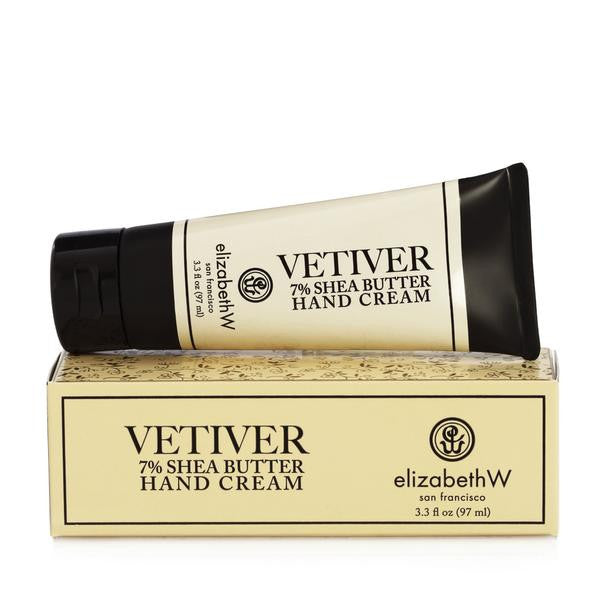 A tube of elizabeth W Signature Vetiver Hand Cream with 7% shea butter lying beside its packaging box on a white background. The tube displays a beige and black botanical cocktail design.