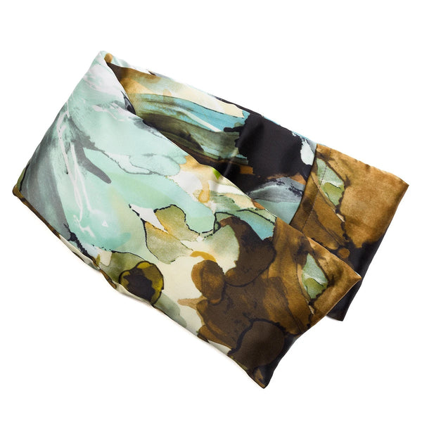 A rectangular, abstract-patterned scarf with shades of green, brown, cream, and black. Elegantly folded to showcase its blend of colors and fluid design, this scarf pairs perfectly with an elizabeth W Silk Hot/Cold Flaxseed Pack - Watercolor for ultimate comfort. The fabric appears soft and lightweight.
