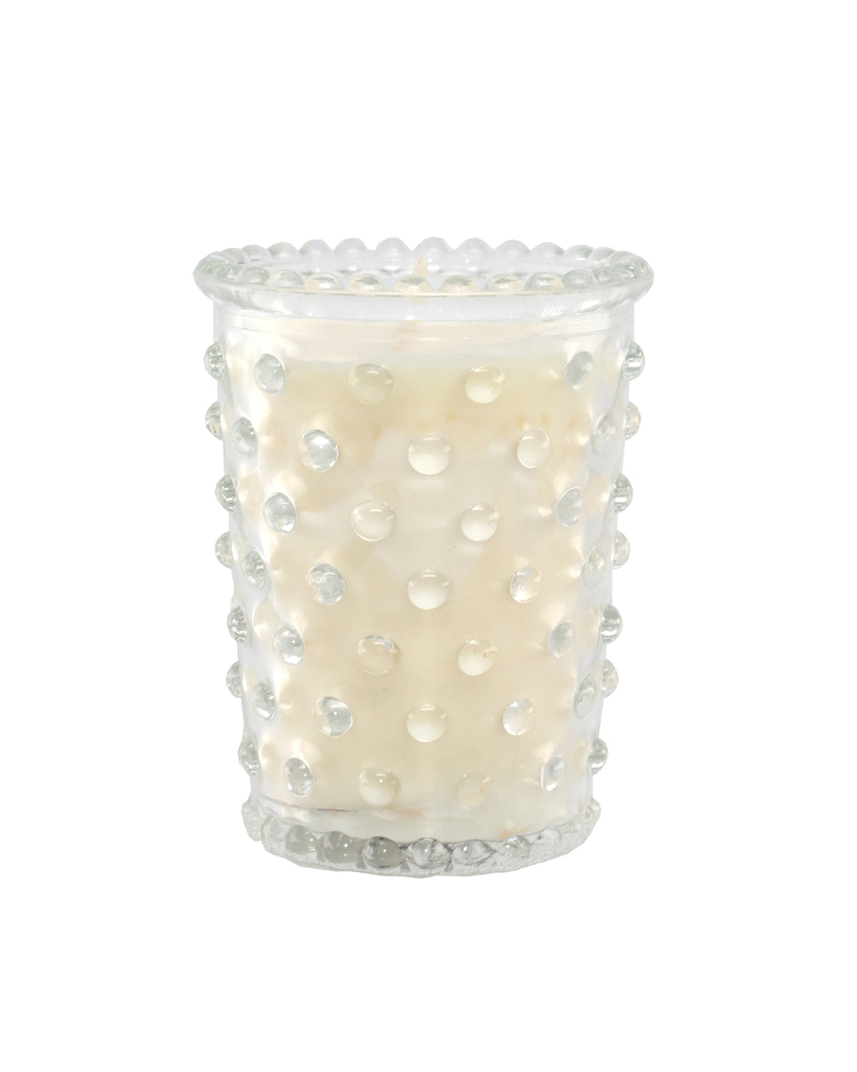 The Simpatico No. 42 White Flower Hobnail Glass Votive Candle by Simpatico is a hand-poured candle in a clear glass holder with a textured, raised dot pattern, shown against a plain white background.