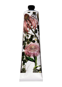 A tube of TokyoMilk Wild Whims No. 80 Bon Bon Shea Butter Lotion by Margot Elena, enriched with Shea Butter and decorated with detailed floral illustrations, featuring pink and purple flowers and green foliage, set against a plain white background.
